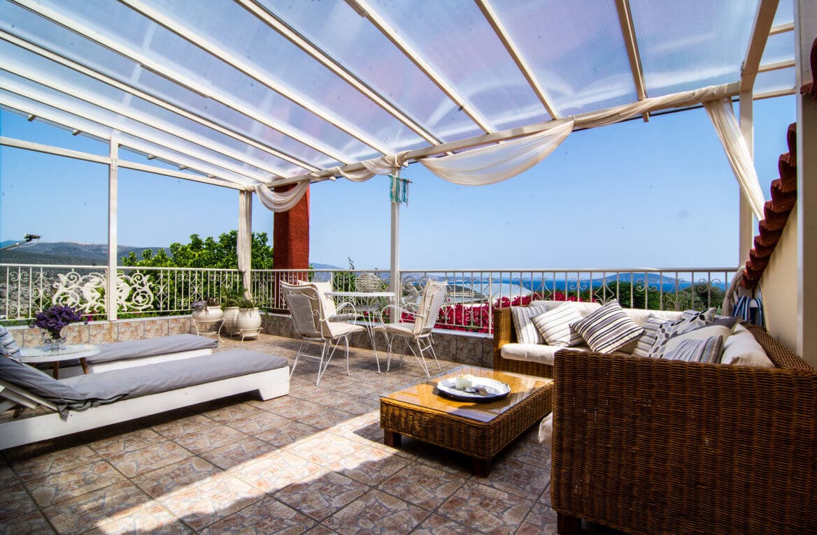 The upper terrace at Villa Rodon, its wicker seating shaded beneath a canopy and the Argolic Gulf beyond